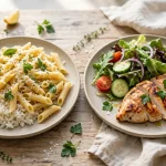 Two plates side by side: a high carb plate of pasta and rice, and a low carb plate of grilled chicken with salad