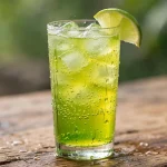 A tall glass of bright green citrus soda with ice cubes and a lime wedge