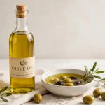 Bottle and small bowl of golden olive oil with olives