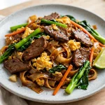 pad see ew calories — a plate of Thai pad see ew noodles with beef, egg and Chinese broccoli
