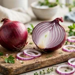 Red onion calories - a whole and halved red onion with slices on a wooden board