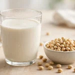 glass of soy milk with soybeans beside it